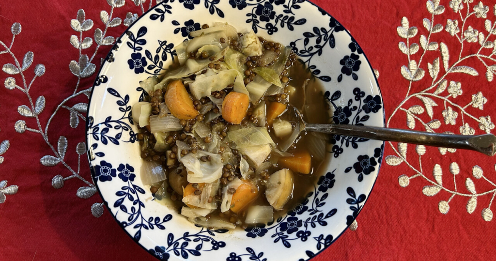 A bowl of black lentil soup with cabbage, sweet potato and carrots