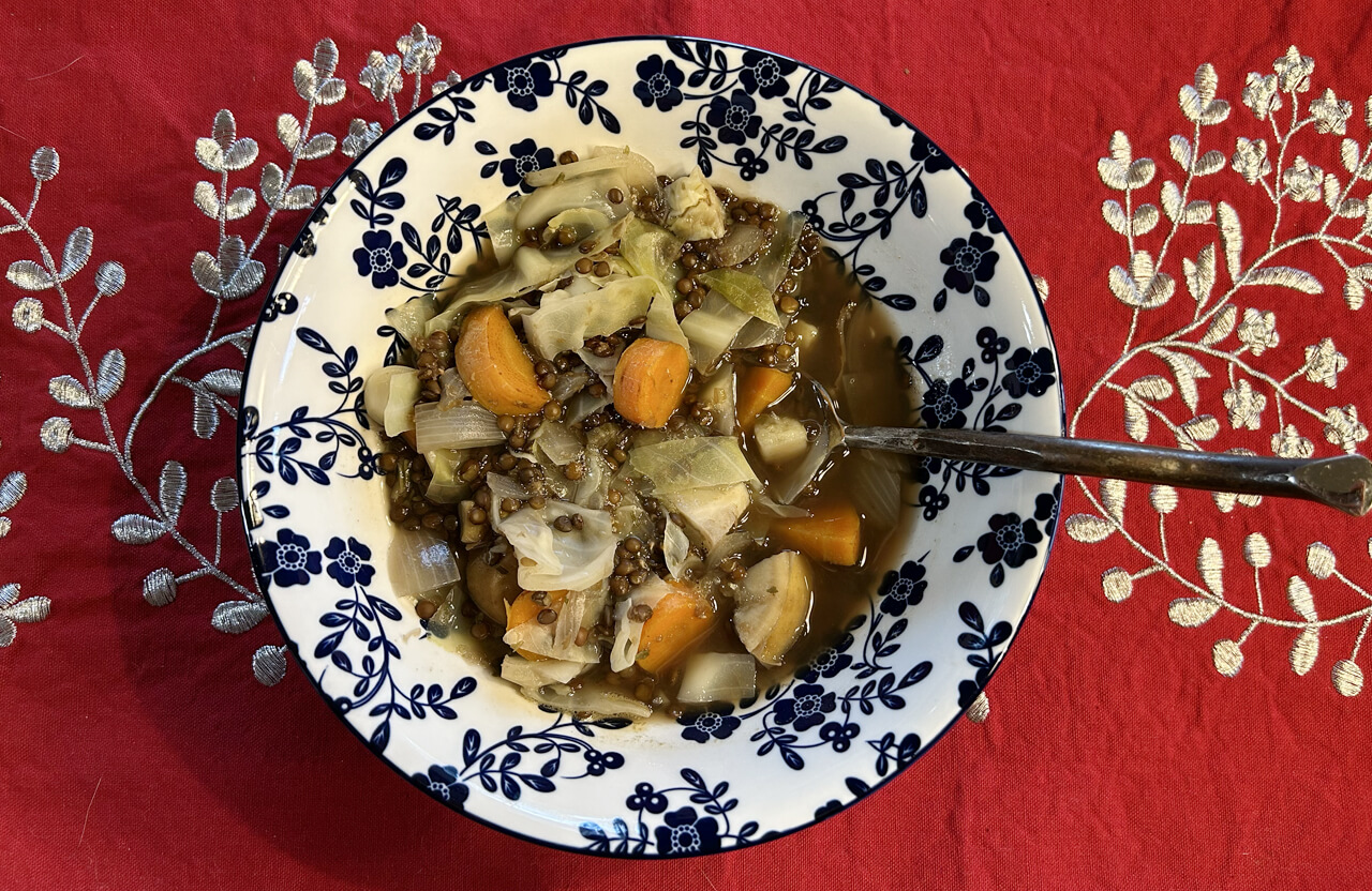 A bowl of black lentil soup with cabbage, sweet potato and carrots