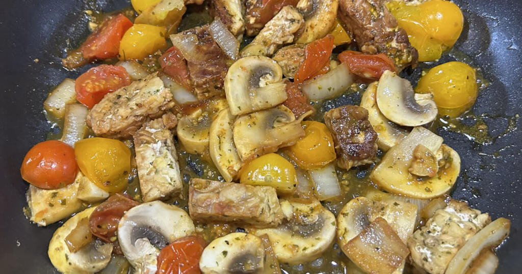 tempeh, tomato, mushrooms, onions and garlic in a frying pan
