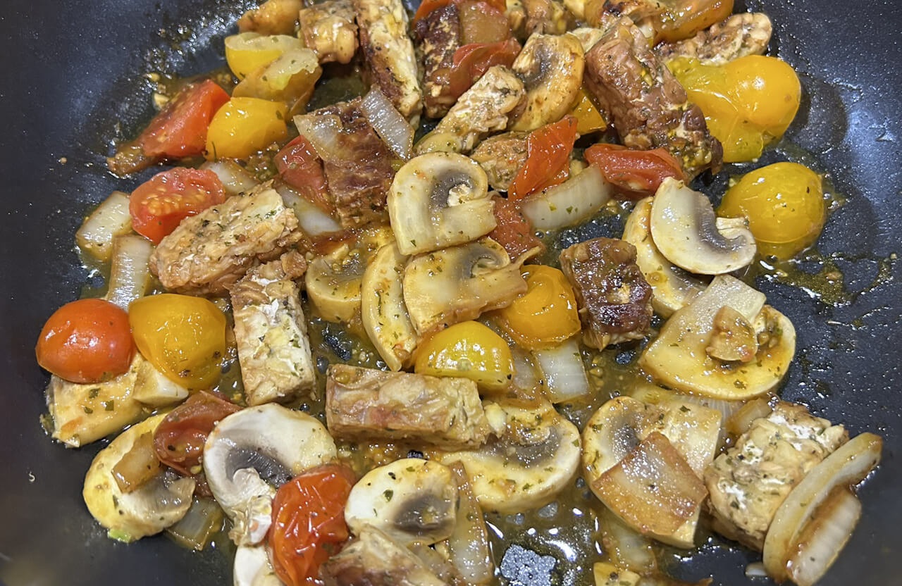 tempeh, tomato, mushrooms, onions and garlic in a frying pan