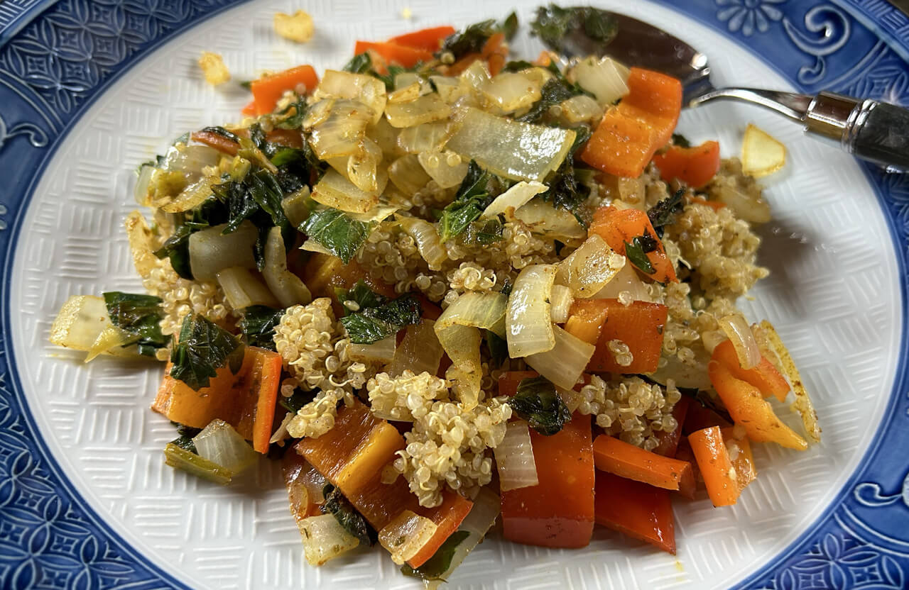 A photo of cooked quinoa with sautéed sweet red pepper, yellow onion and celery leaves