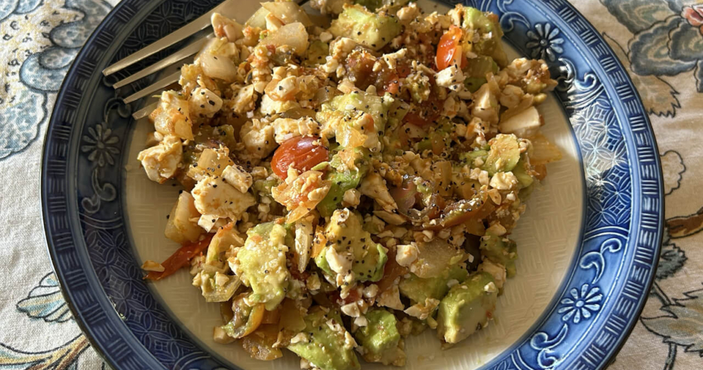 a plate with scrambled tofu, salsa, cherry tomatoes and avocado