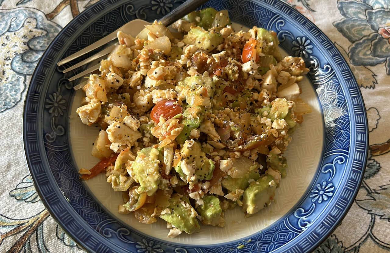 a plate with scrambled tofu, salsa, cherry tomatoes and avocado